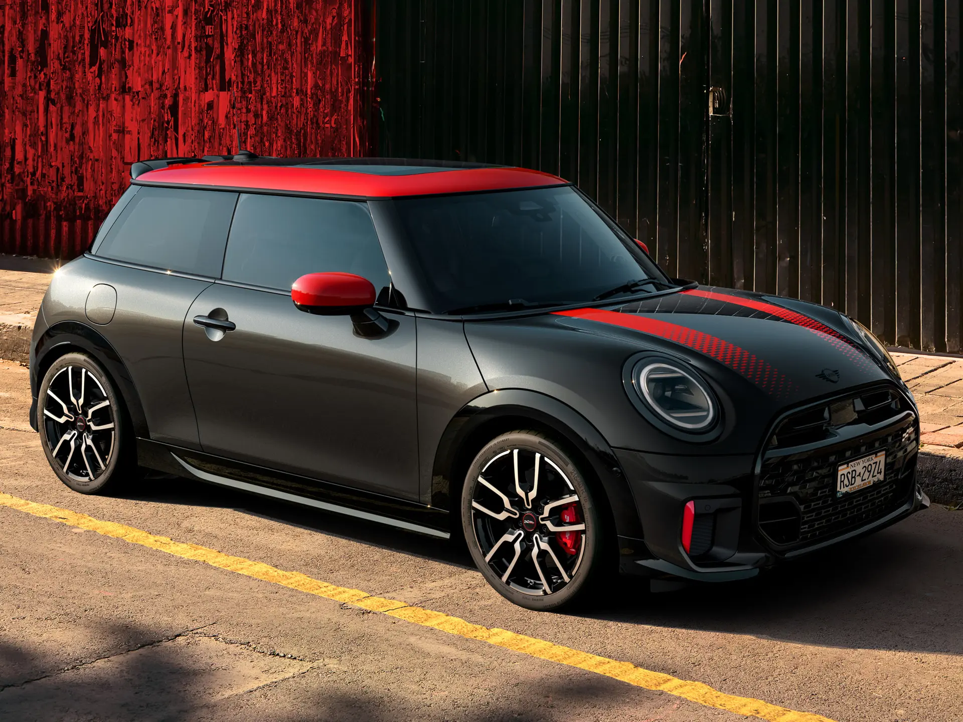 MINI John Cooper Works 3ja dyra í Midnight Black með Chili Red þaki og speglahlífum og rauðum sportröndum, hliðarsýn, lagt í götu.