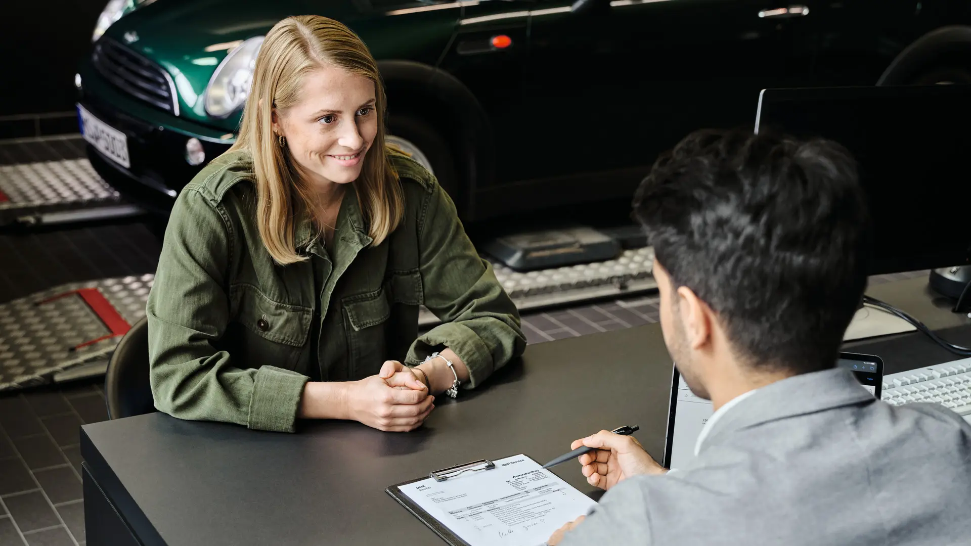 MINI miðstöð með ráðgjafa sem ráðgjafar viðskiptavini um þjónustuköðu hennar, bæði sitjandi við borð.