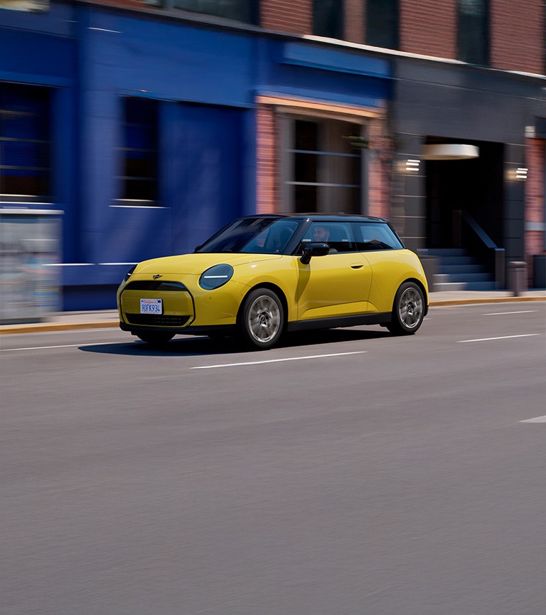 Gulur rafknúinn MINI Cooper á ferð í borgarumhverfi